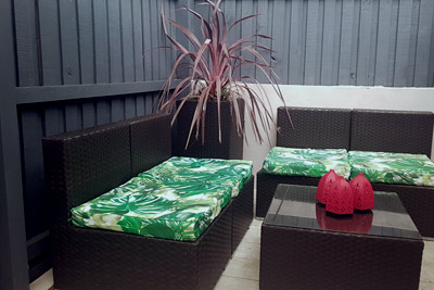 AFTER: Fence painted, floor tiled, modern outdoor furniture and a plant in an oversized garden pot.