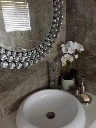 Chic bathroom mirror, a pot of orchid flowers and white contemporary blinds work well for any bathroom.