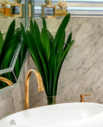 Elegant look of Clivia leaves in our renovated bathroom with gold bathroom accessories and carrara marble tiles .